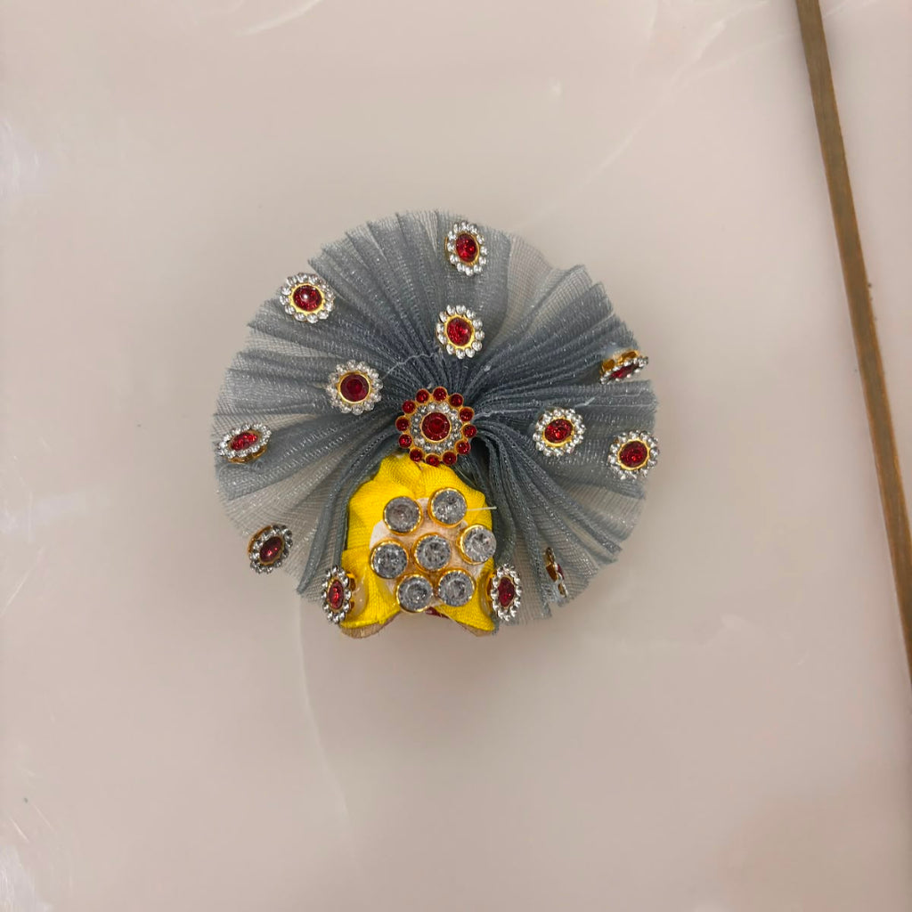 Decorative hair clip with gray tulle, red stones, and yellow center on a white background
