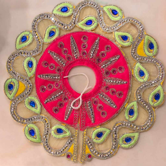 Handcrafted fuchsia pink designer dress and matching yellow crown for Ladoo Gopal Ji, featuring peacock-plume borders and blue gemstone accents.