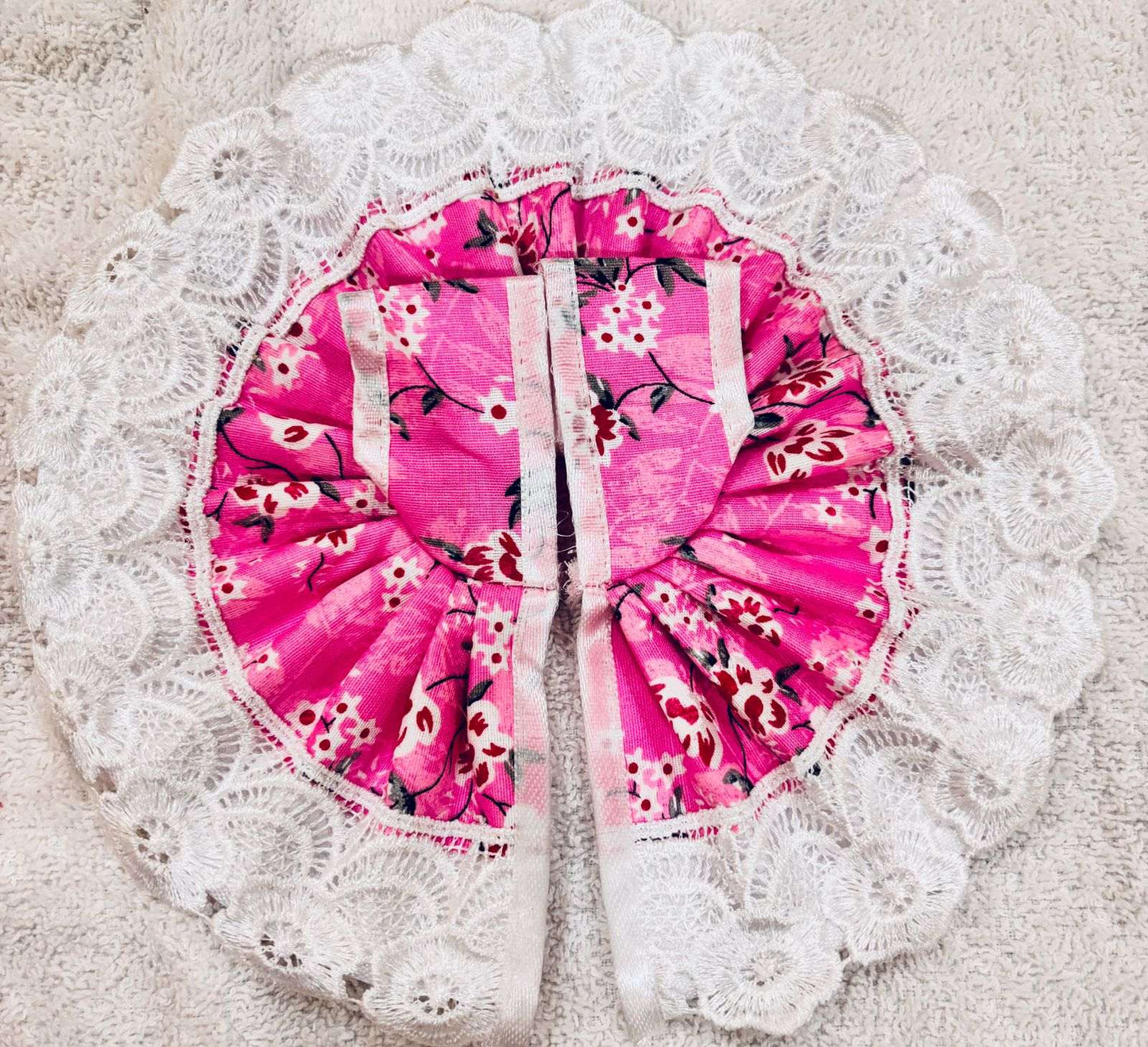 Pink floral-patterned baby seat cover on a white lace doily