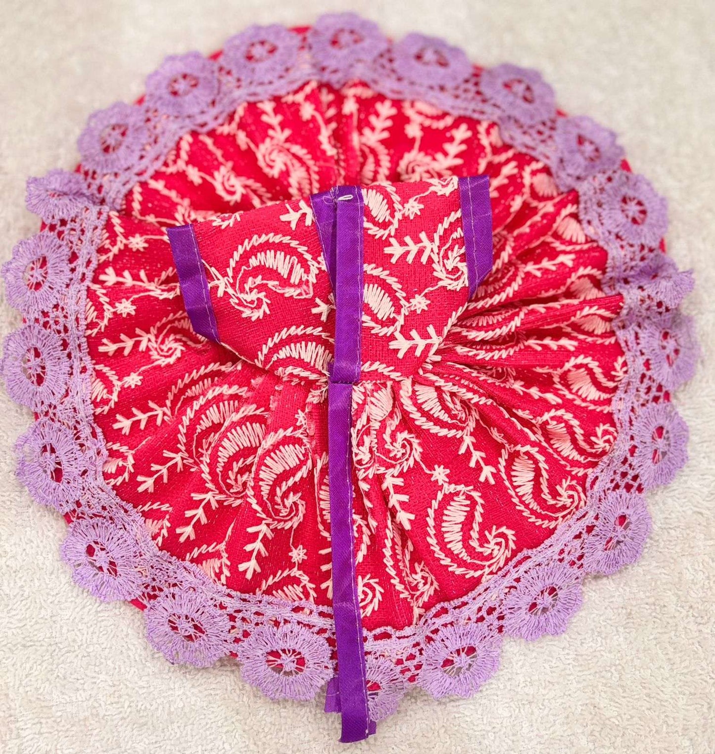 Red fabric with white patterns and purple trim on a beige background