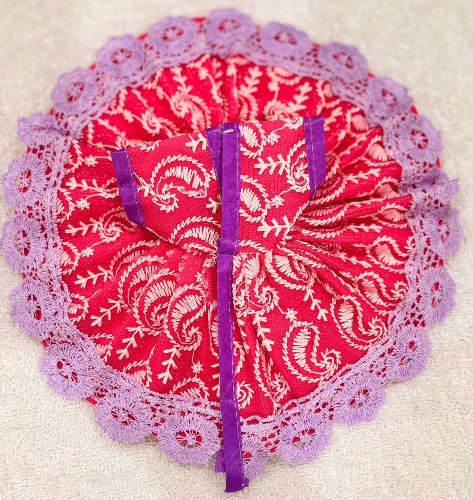 Red fabric with white patterns and purple trim on a beige background