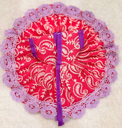 Red fabric with white patterns and purple trim on a beige background
