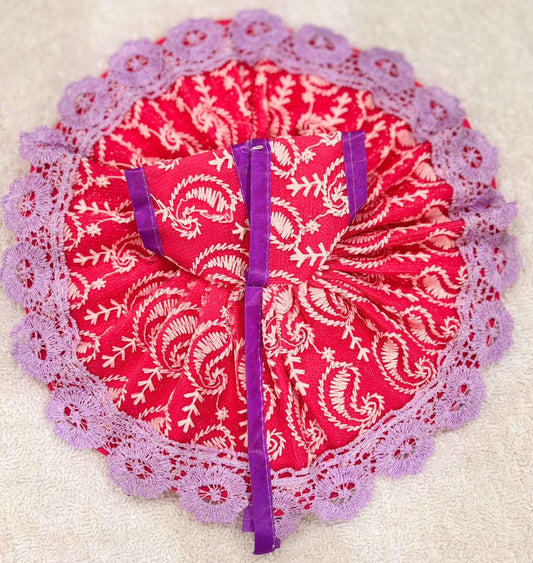Red fabric with white patterns and purple trim on a beige background