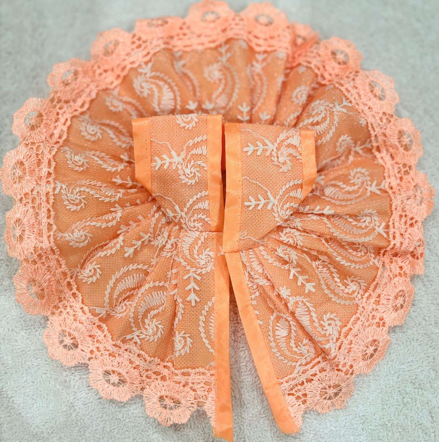 Peach-colored lace bow on a light gray background