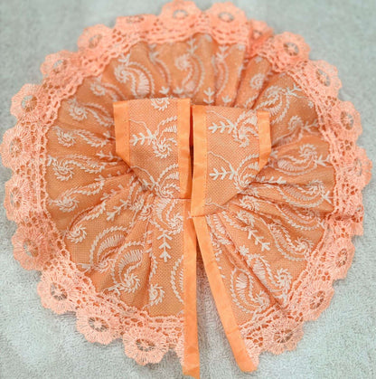 Peach-colored lace bow on a light gray background