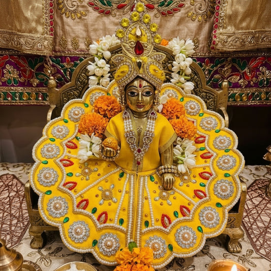 Bhavyaam Pitambar Vaibhav Poshak for Ladoo Gopal Ji featuring a handcrafted yellow designer dress with pearl embroidery, kundan embellishments, floral detailing, and a matching royal mukut.