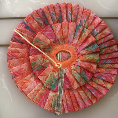 Colorful fabric-covered object with a central circular cutout on a white surface