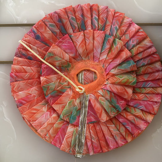 Colorful fabric-covered object with a central circular cutout on a white surface