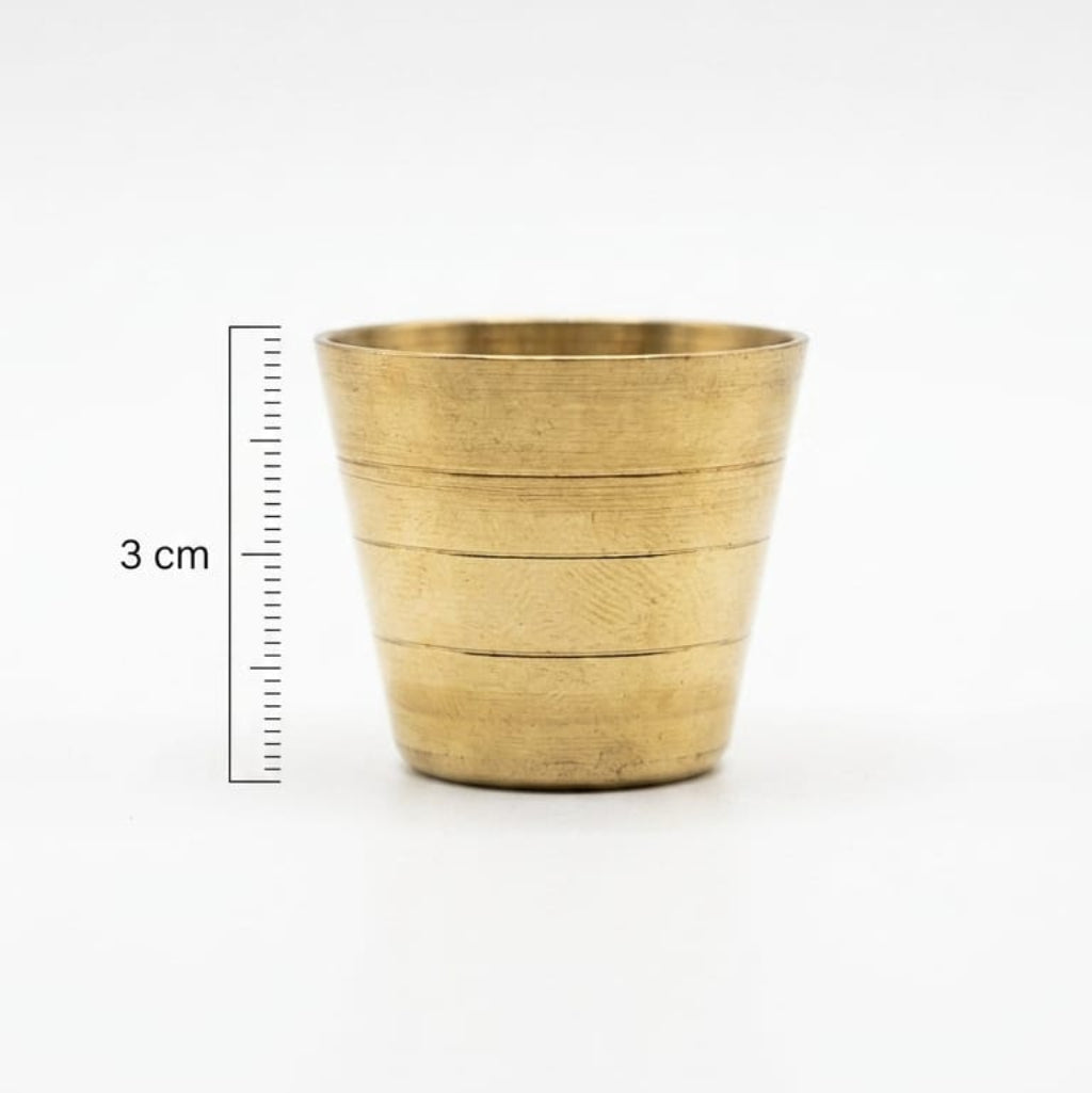 Brass cup with measurement scale on a white background