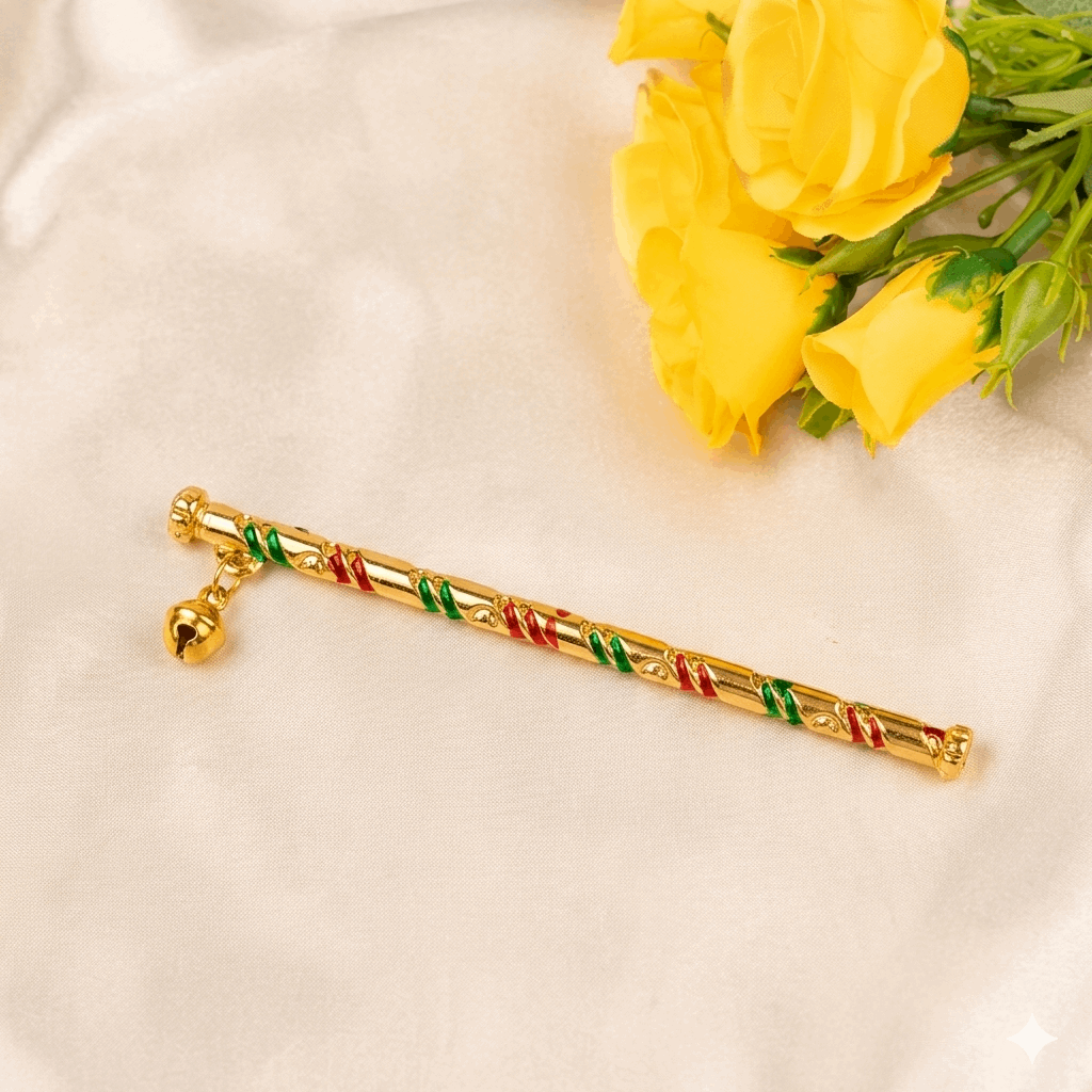 Gold bansuri with red and green accents on a white surface with yellow flowers.