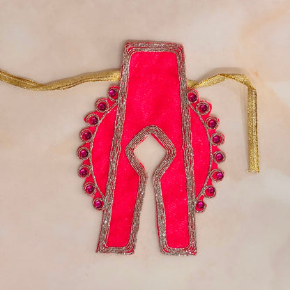 A bright pink embroidered blouse yoke or neckline piece with silver metallic borders, pink sequins, and a gold tie string, displayed on a light beige surface.
