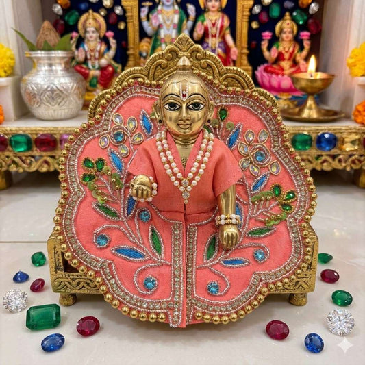 Decorative idol in a pink and gold outfit with gemstones on a white surface.
