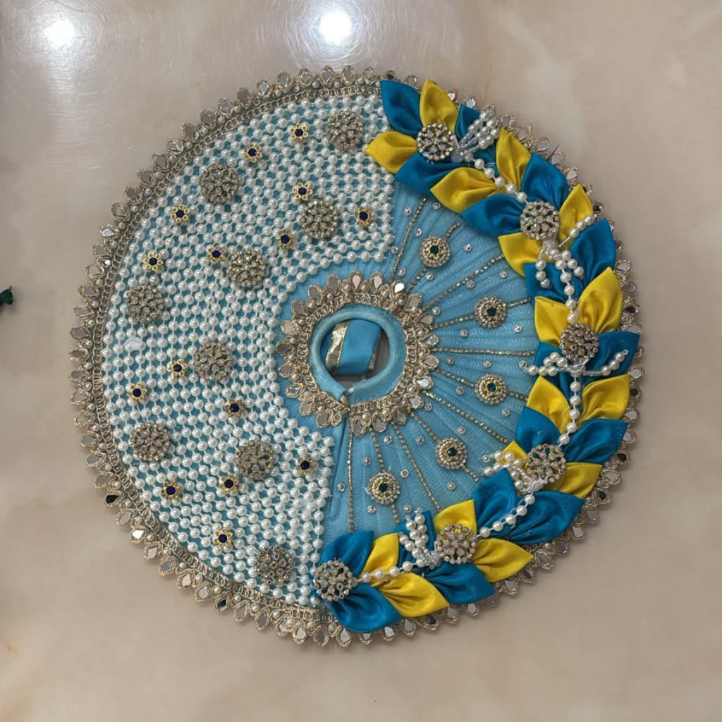 Handcrafted sky-blue and yellow designer dress and matching crown for Ladoo Gopal Ji, featuring pearl work and intricate petal detailing.