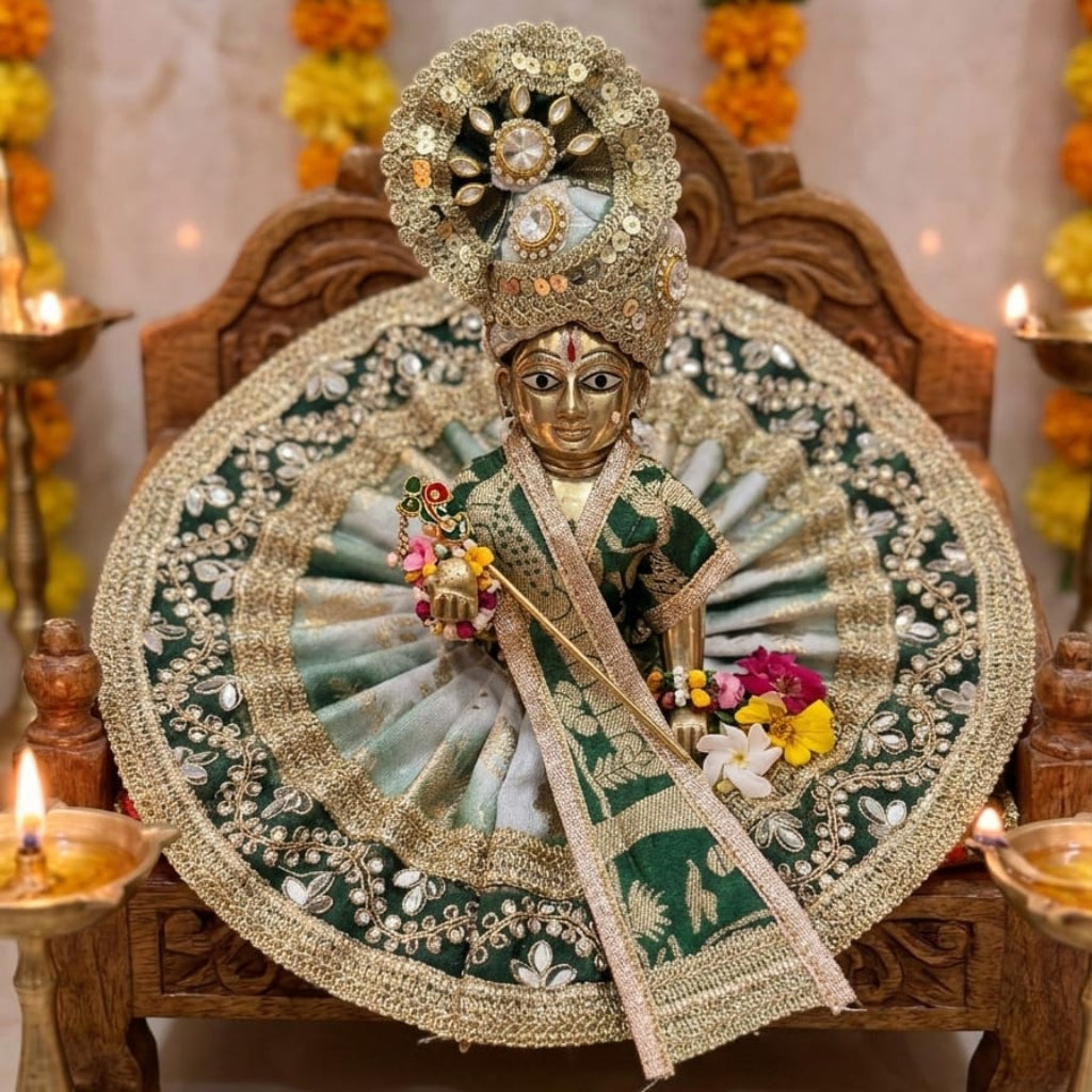 Handcrafted emerald green brocade designer dress and matching heavy gold crown for Ladoo Gopal Ji, featuring mirror-work lace borders.