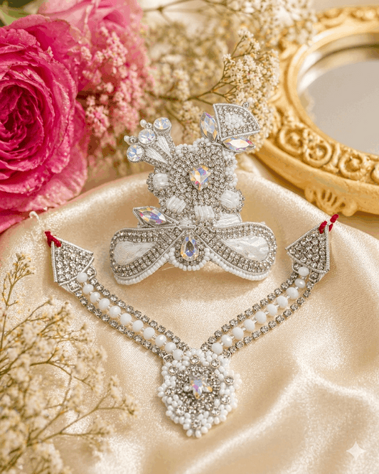 Decorative brooch with gemstones on a beige fabric background with pink roses and gold frame.