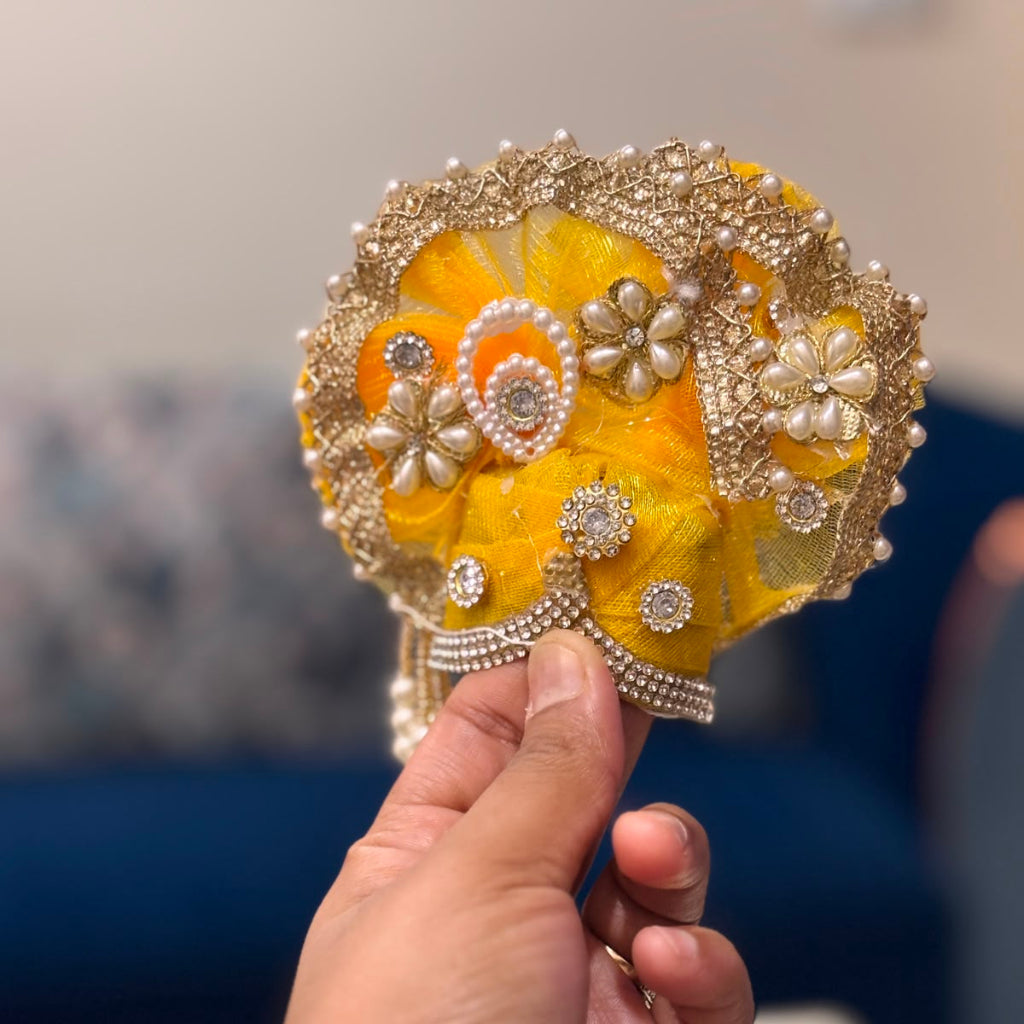 Handcrafted golden-yellow designer dress and matching crown for Ladoo Gopal Ji, adorned with pearl flowers and sparkling crystals.