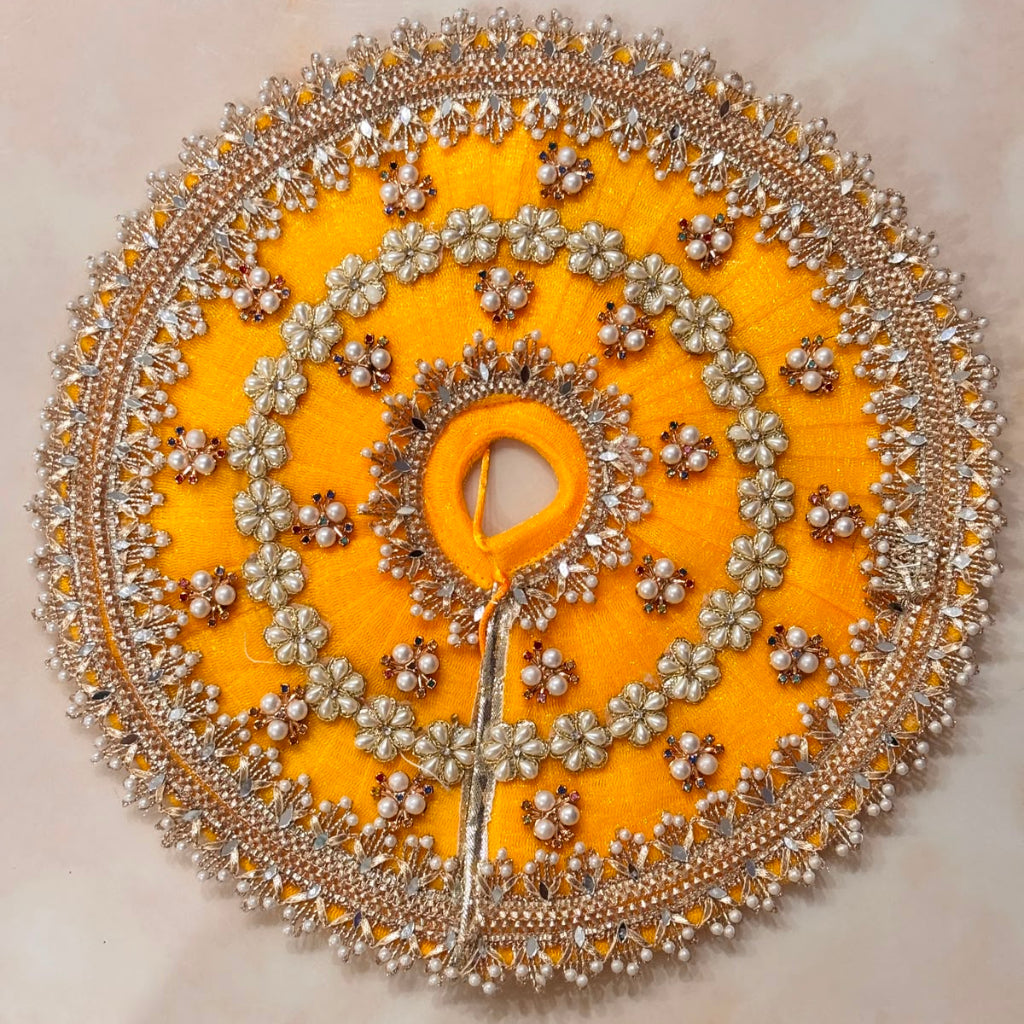 Handcrafted golden-yellow designer dress and matching crown for Ladoo Gopal Ji, adorned with pearl flowers and sparkling crystals.