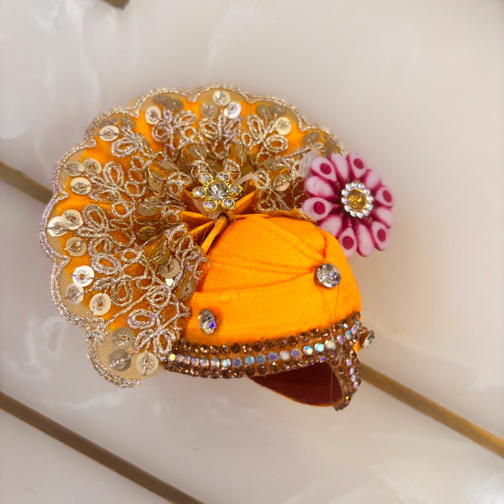 Decorative yellow turban with intricate gold and silver embellishments on a white background