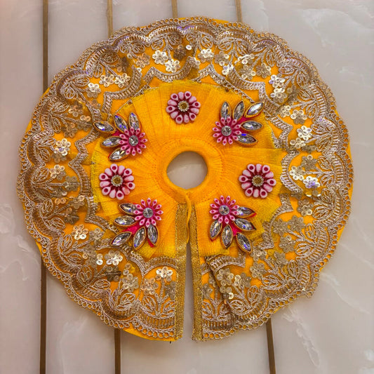 Decorative yellow fabric piece with gold embroidery on a marble surface