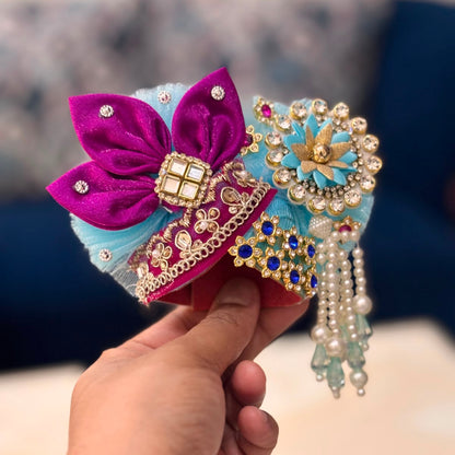Handcrafted sky-blue designer dress and matching crown for Ladoo Gopal Ji, featuring Radha-Krishna figures, purple petal folds, and pearl detailing